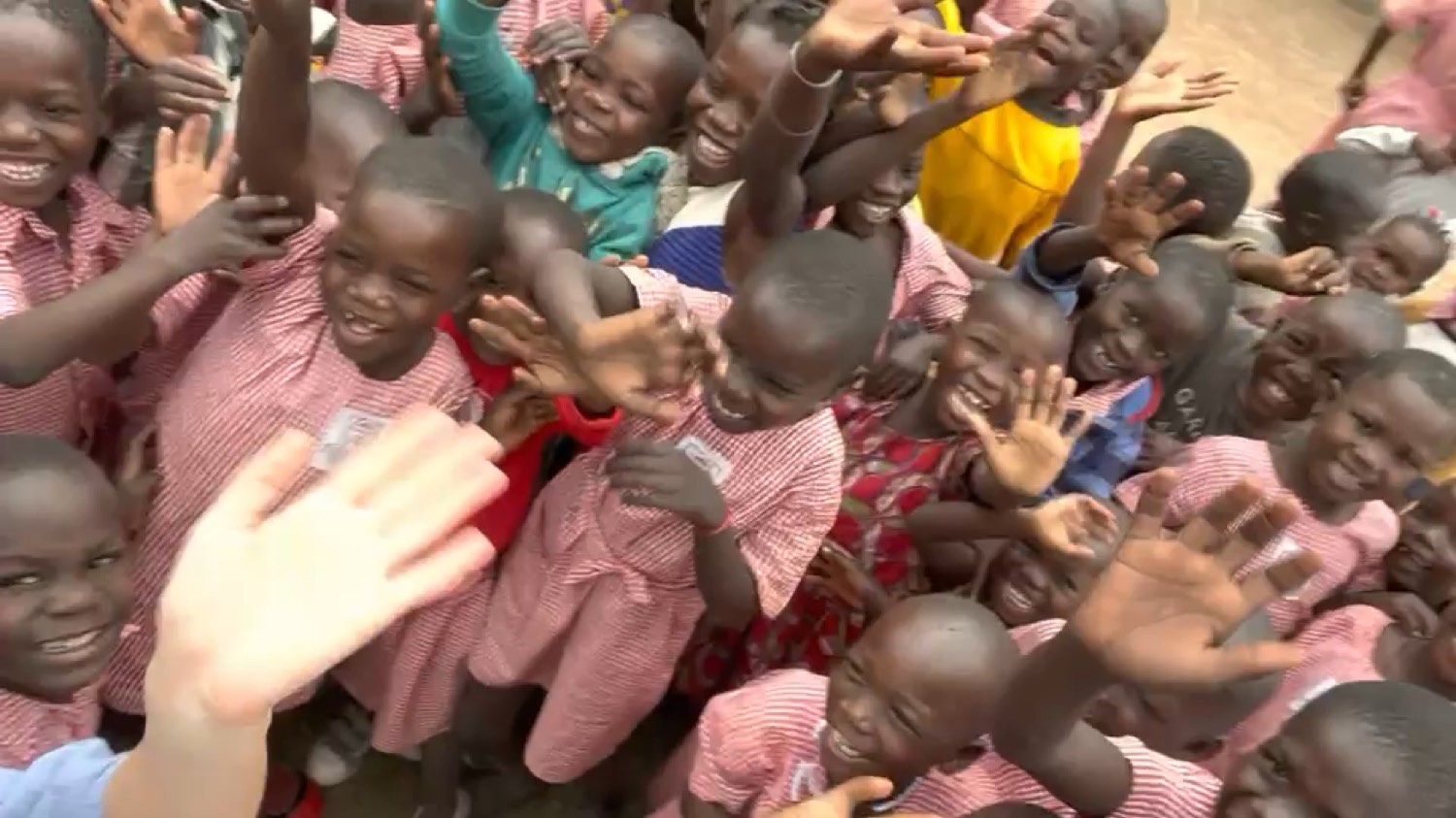 Children of the Sikiliza Leo nursery school in Mulanda waving and laughing at the camera.