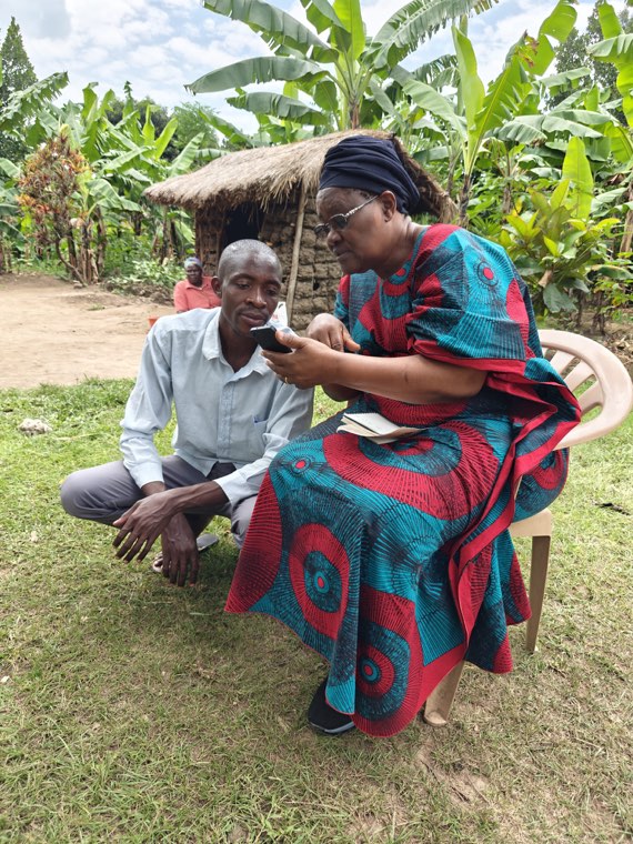 A Sikiliza Leo child monitor talking with a grandmother during a home visit.