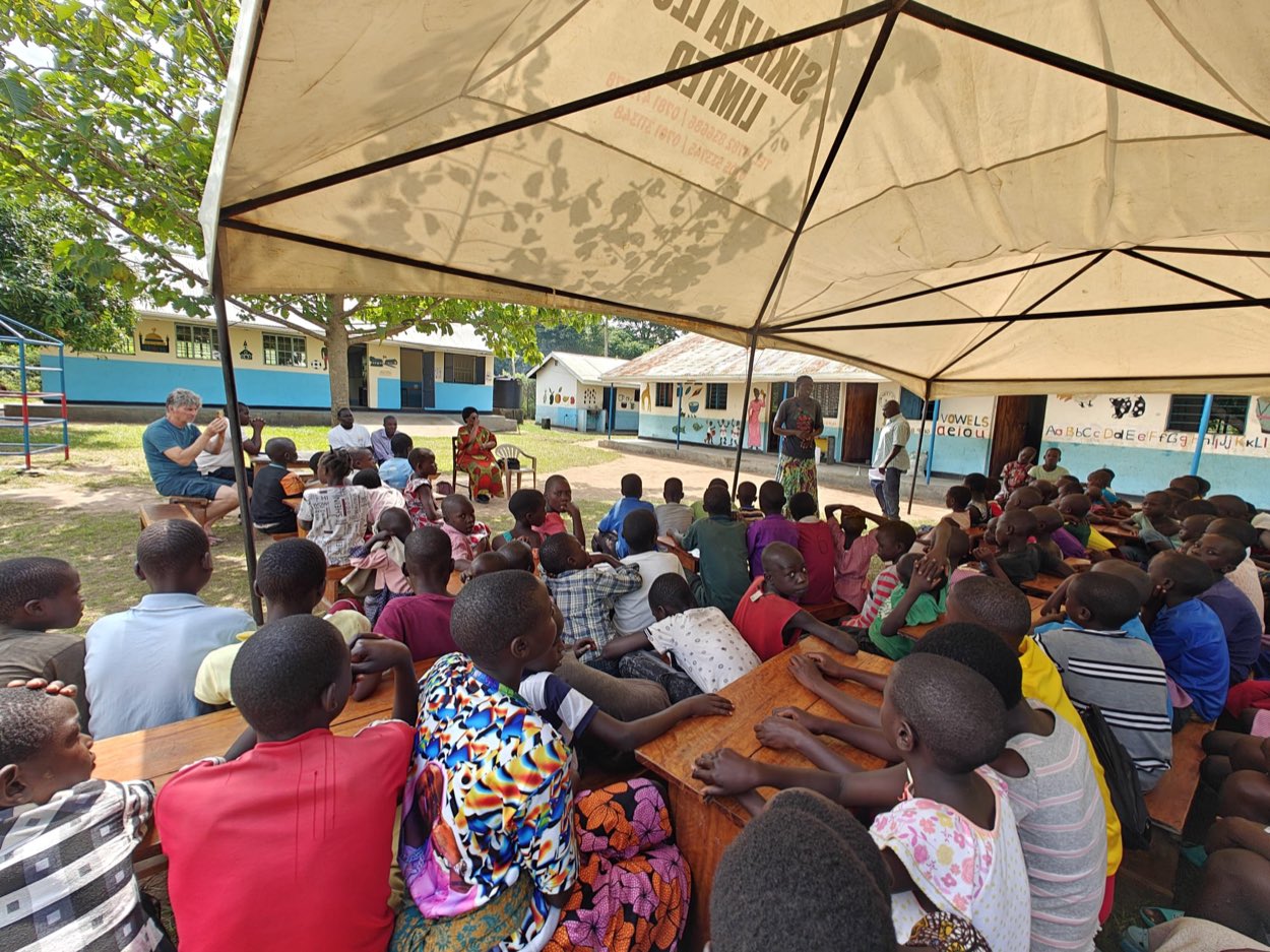 Children and carers together under a Sikiliza Leo tent on the school grounds in Mulanda.
