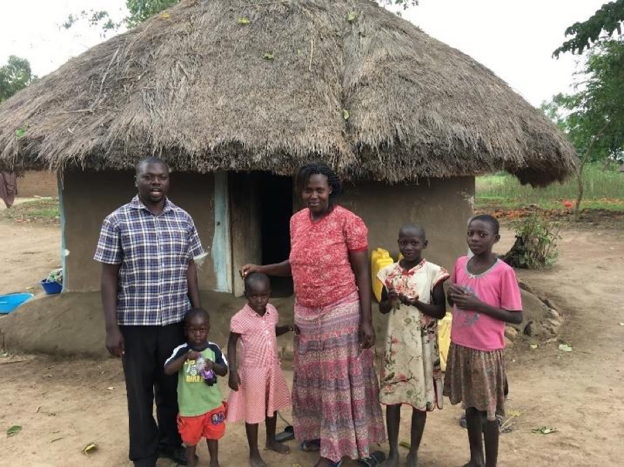 Charles Opio met zijn vrouw Helen en hun kinderen voor hun huis.