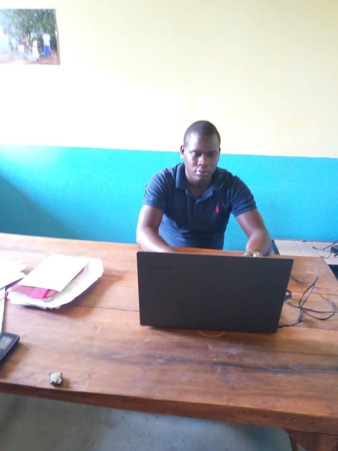 James Ochola aan zijn bureau met laptop in de kleuterschool.